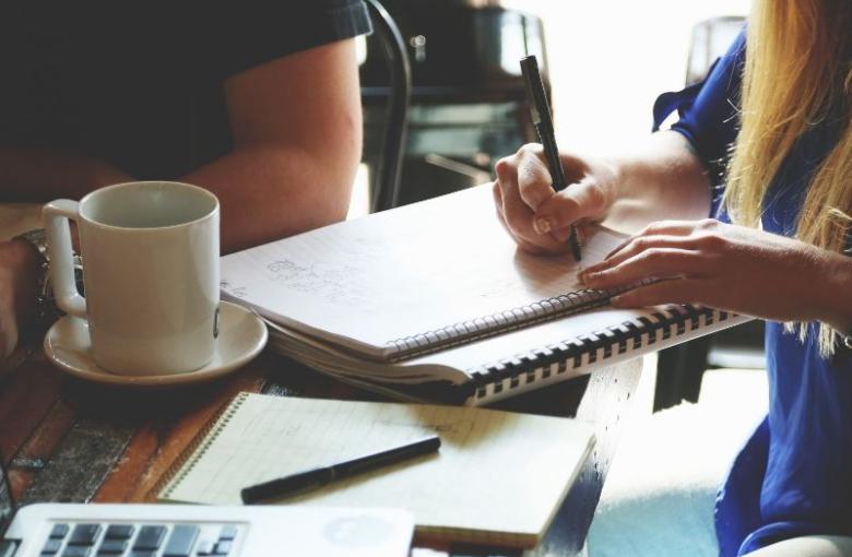 A woman writting on the notebook